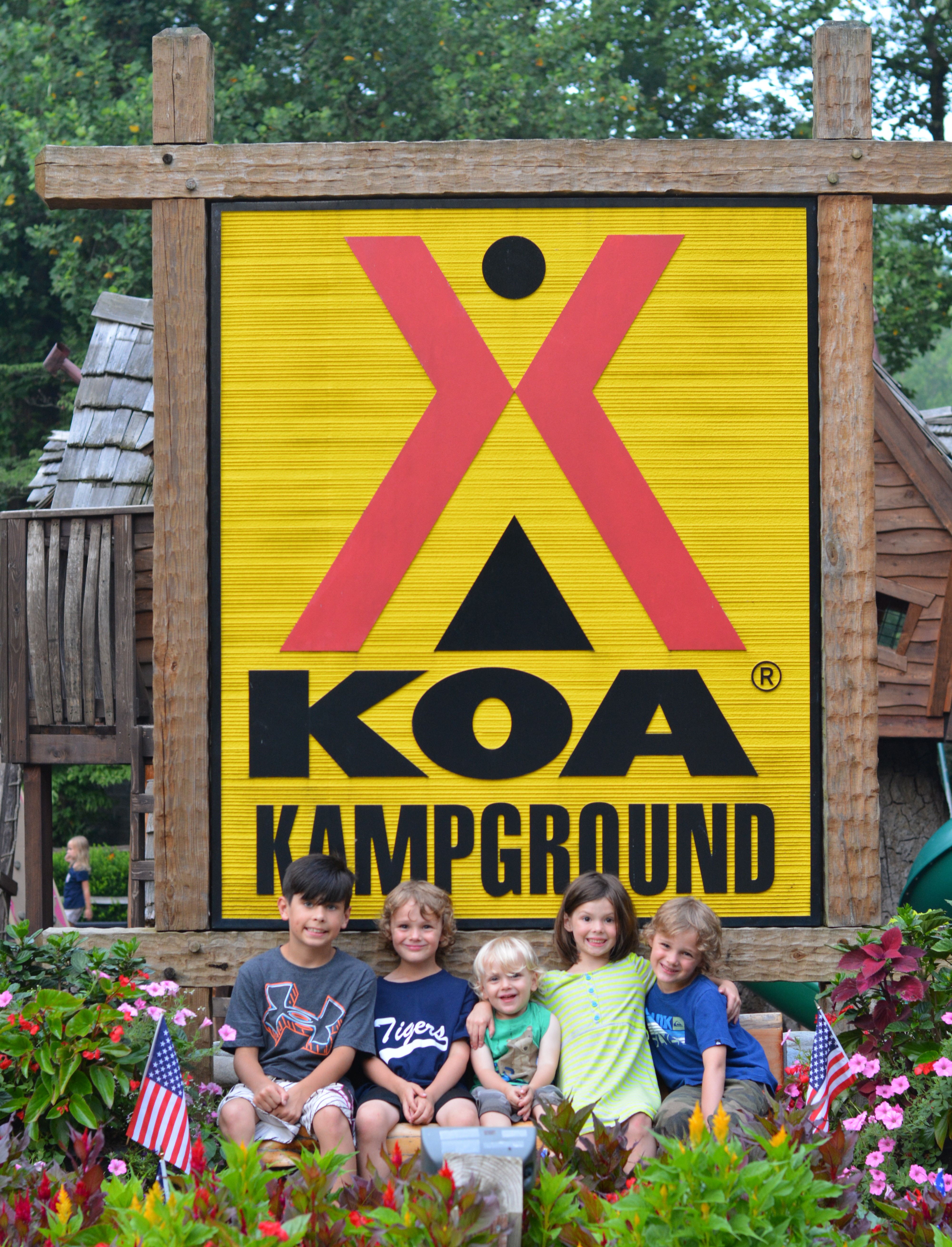 Children sitting in front of KOA logo