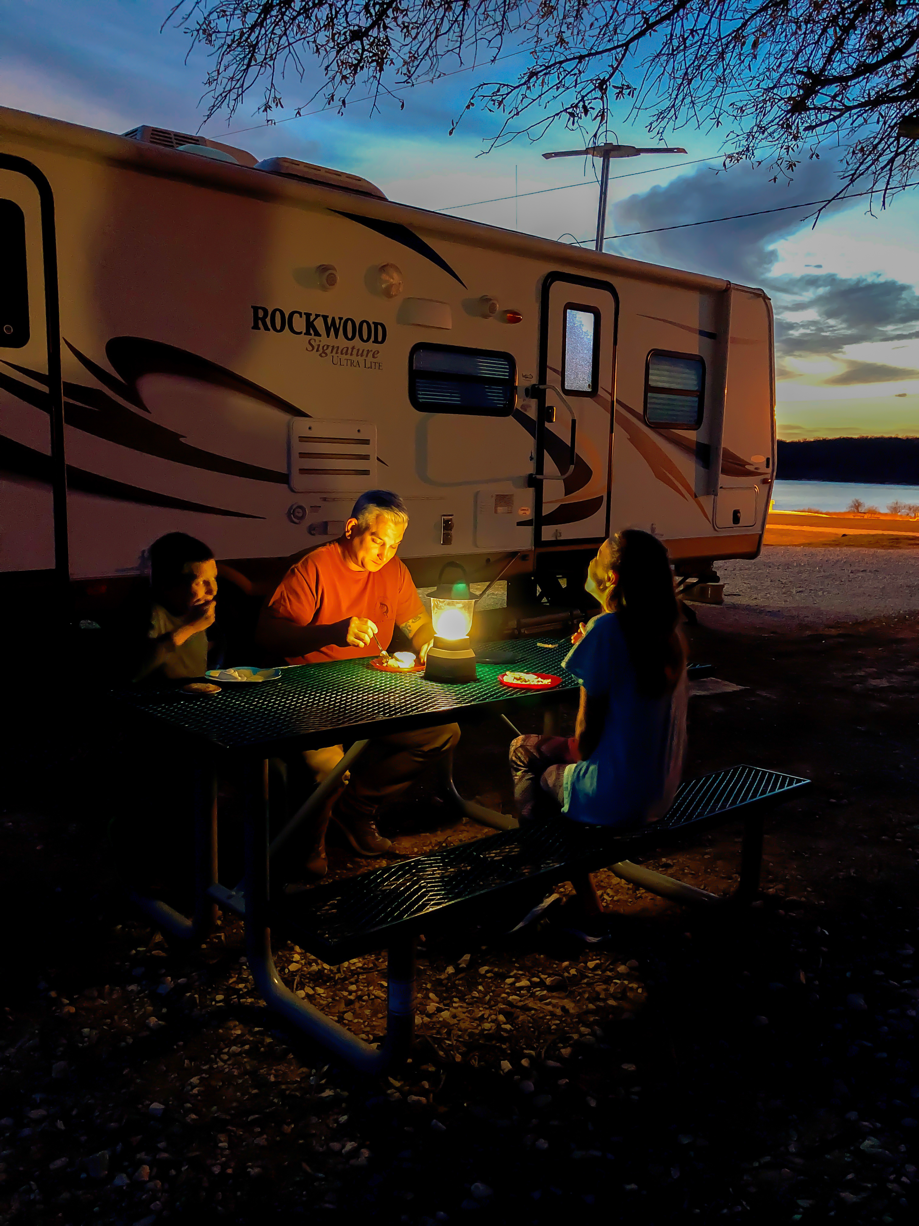 Man and Two Children Eating Outside of RV at night
