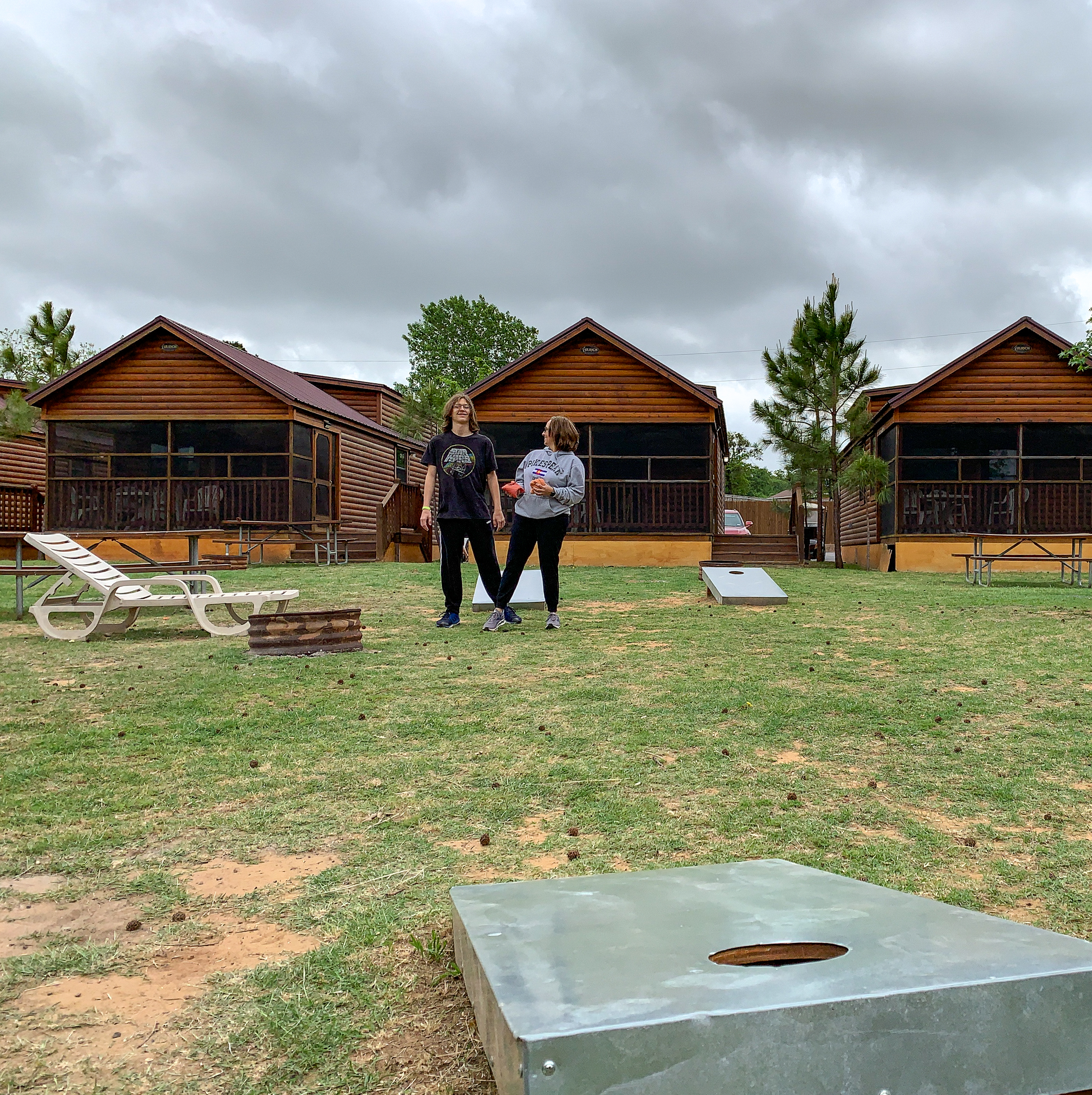 Woman and Boy Playing Cornhole in front of Cabin