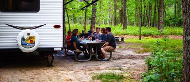 RV in the woods with family eating at the table