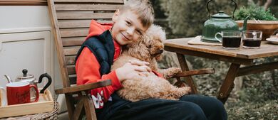 Boy sitting with puppy outside RV