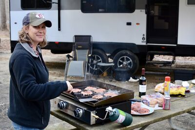 Woman grilling burgers at RV campsite