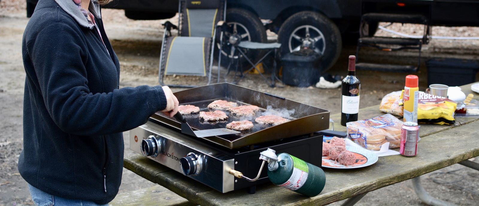 Woman grilling burgers at RV campsite