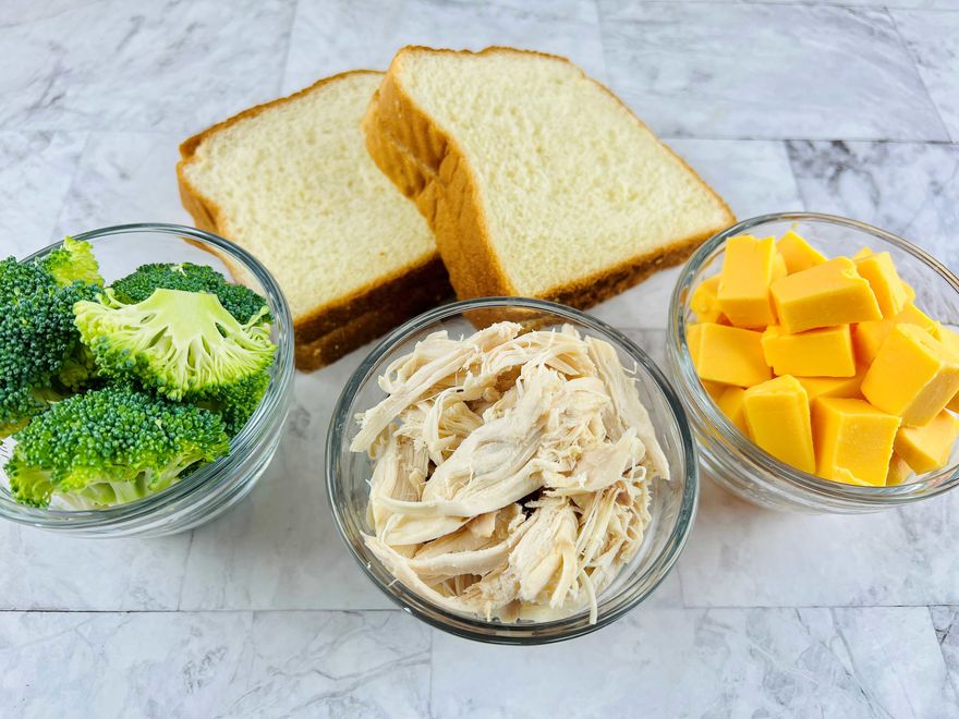 Gather pie iron, slices of white bread, cubed Velveeta cheese, broccoli florets, and shredded cooked turkey breast.