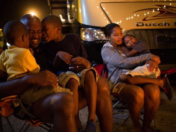 Family sits outside their RV enjoying the evening