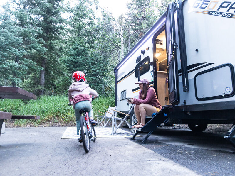 A girl rides her bike around her family's RV campsite