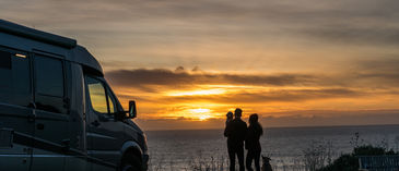 family next to water at sunset